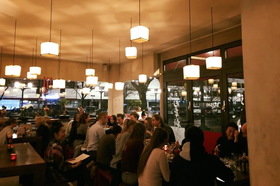 People eating at Sushi Berlin, cubic decoration lamps and glass walls to the street